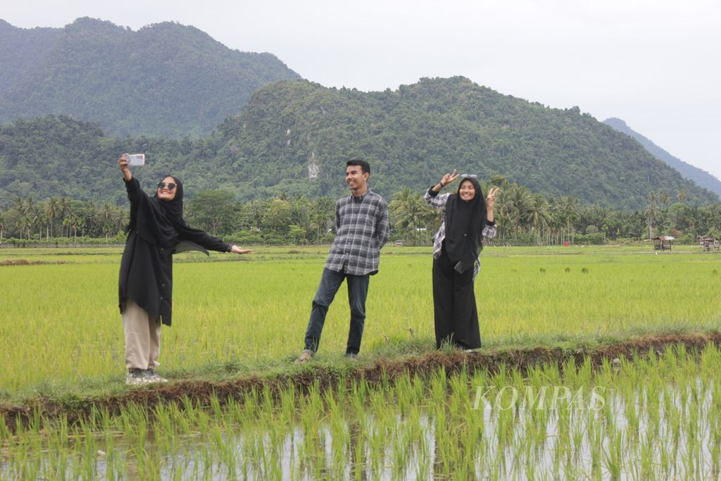 Tiga wisatawan lokal berfoto di hamparan sawah di Desa Geunteut, Kecamatan Lhoong, Kabupaten Aceh Besar, Aceh, Sabtu, 4 Juni 2022. Desa Geunteut dikenal dengan durian dan nilam. Kini kedua komoditas itu dikemas sebagai paket wisata.