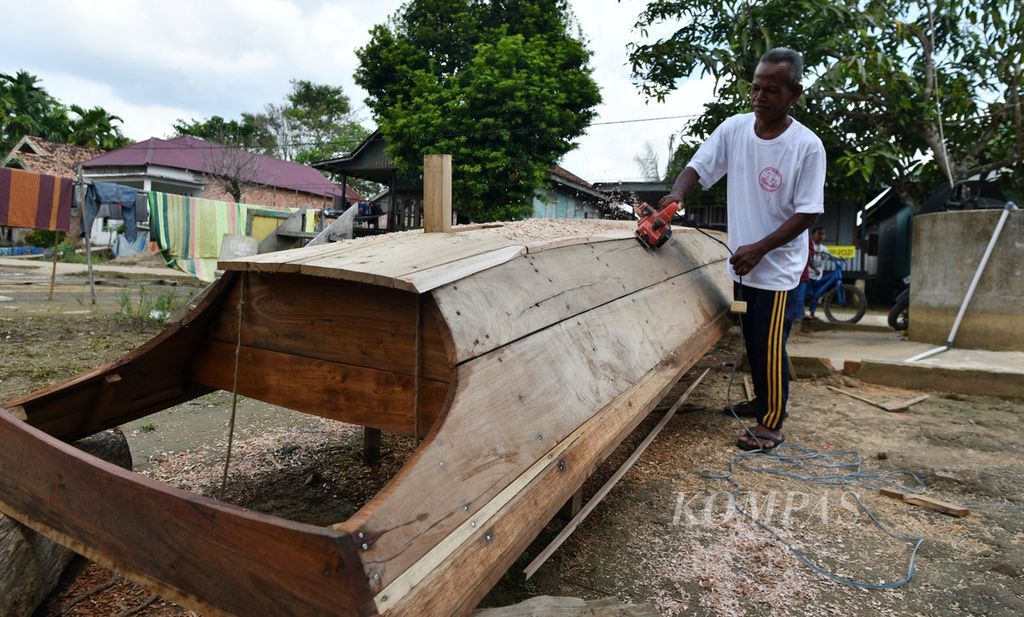 Ependi menyelesaikan pembuatan perahu dari kayu meranti di halaman rumahnya di Desa Dusun Mudo, Kecamatan Taman Rajo, Muaro Jambi, Jambi, Rabu (10/7/2024). 