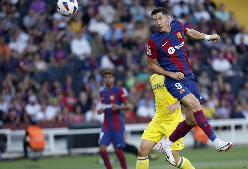 Pemain Barcelona, Robert Lewandowski, menyundul bola pada laga Liga Spanyol melawan Cadiz di Stadion Camp Nou, Barcelona, Spanyol, Minggu (20/8/2023). 