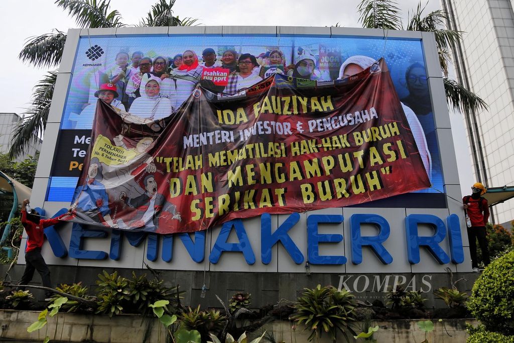 Buruh industri padat karya memasang spanduk penolakan saat berunjuk rasa di depan Gedung Kementerian Ketenagakerjaan, Jakarta, Selasa (23/5/2023). Mereka menuntut Menteri Ketenagakerjaan mencabut Permenaker No 5 Tahun 2023 yang dianggap melegalkan pemotongan upah buruh di industri padat karya orientasi ekspor hingga 25 persen.