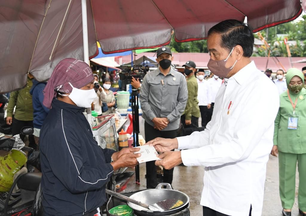 Presiden Joko Widodo menyerahkan bantuan modal kerja dan bantuan langsung tunai minyak goreng kepada pedagang kaki lima dan pedagang Pasar Angso Duo, Kota Jambi, Kamis (7/4/2022)