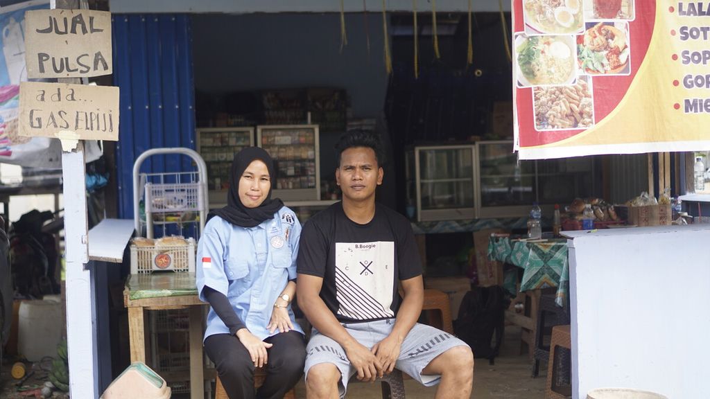 Yati Dahlia (32) duduk bersama suaminya di halaman warungnya di Desa Bumi Harapan, Kecamatan Sepaku, Penajam Paser Utara, Kalimantan Timur, Jumat (17/3/2023).