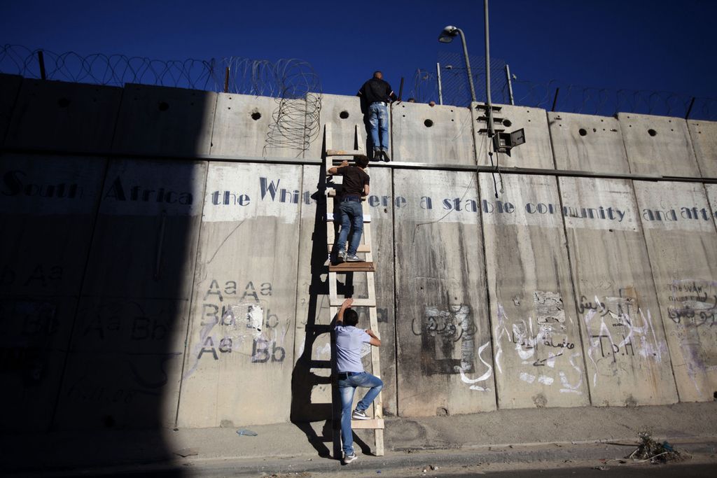 Foto yang diambil pada 11 Juli 2014 memperlihatkan sejumlah warga Palestina mencoba melewati tembok pemisah menggunakan tangga agar bisa menjalankan shalat di Mesjid Al Aqsa. Lembaga advokasi global, Selasa (1/2/2022) mengeluarkan laporan yang menyebut bahwa Pemerintah Israel telah menjalankan kebijakan apartheid terhadap rakyat Palestina.(AP Photo/Majdi Mohammed)