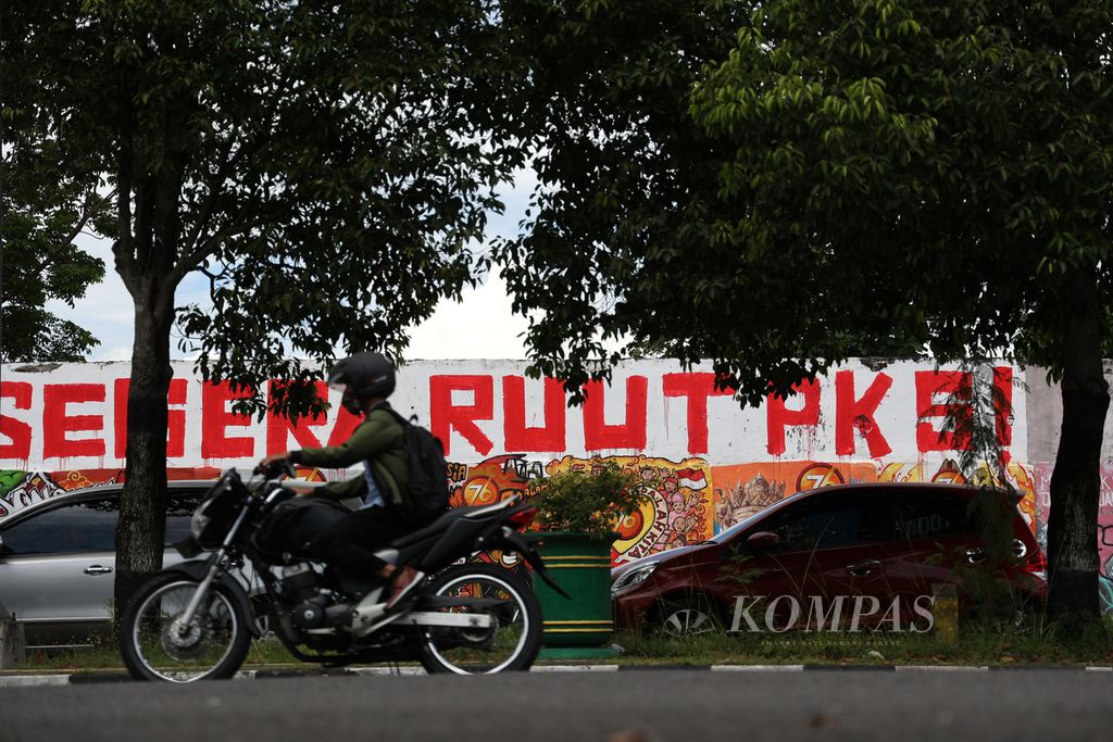 Mobil diparkir di depan mural berisi seruan untuk mendorong pengesahan Rancangan Undang-Undang Tindak Pidana Kekerasan Seksual yang dibuat di tembok Stadion Kridosono, Yogyakarta, Senin (10/1/2021). 