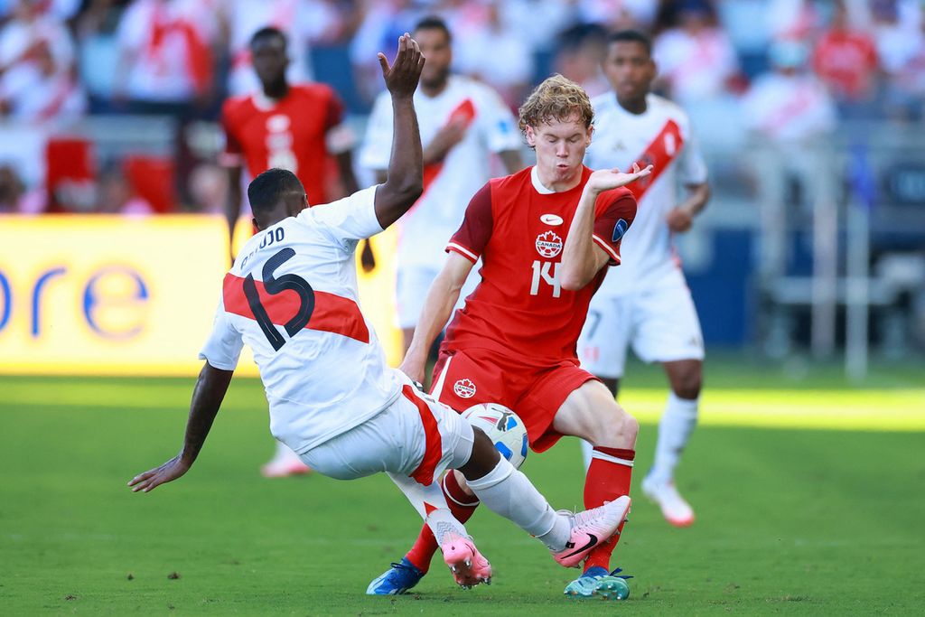 Peruvian player Miguel Araujo (L) tackles Canadian player Jacob Shaffelburg during the Copa America 2024 Group A match in Kansas City, the United States, Wednesday (26/6/2024) WIB. Araujo was given a red card for the foul. Canada won with a score of 1-0.