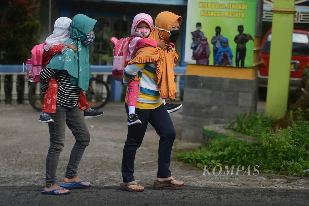 Ibu rumah tangga menggendong anak balita mereka menuju tempat pendidikan anak usia dini untuk memperoleh materi ajar di Desa Keditan, Ngablak, Magelang, Jawa Tengah, Selasa (21/7/2020).