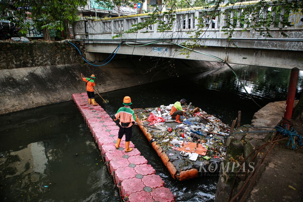 Petugas Penanganan Prasarana dan Sarana Umum (PPSU) mengumpulkan sampah plastik di aliran air menuju Waduk Melati, Tanah Abang, Jakarta Pusat, Rabu (21/12/2022). Sampah dari kemasan makanan tersebut berasal dari lingkungan sekitar yang banyak terdapat pedagang kaki lima. 