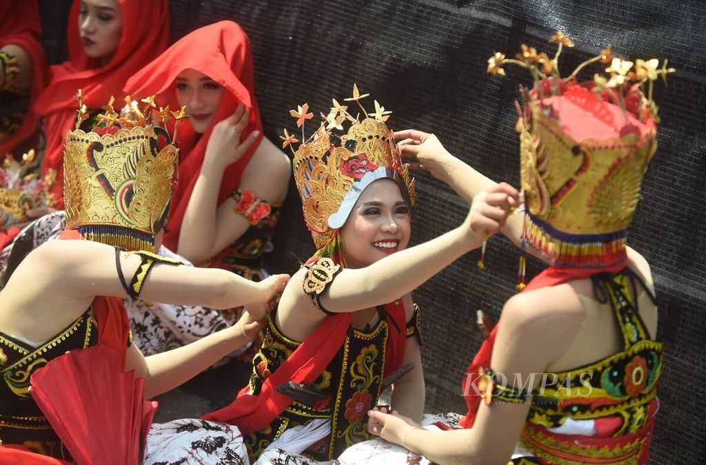 Penari saling merapikan busana saat menunggu waktu untuk tampil dalam Festival Gandrung Sewu 2022 di Pantai Marina Boom, Kabupaten Banyuwangi, Jawa Timur, Sabtu (29/10/2022).