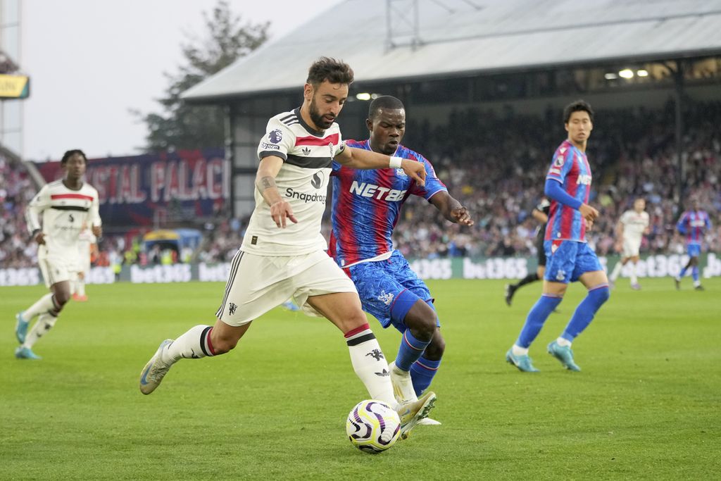 Pemain Manchester United, Bruno Fernandes (kiri), menggiring bola dengan dibayangi pemain Crystal Palace, Tyrick Mitchell, pada laga Liga Inggris di Stadion Selhurst Park, London, Sabtu (21/9/2024). Laga berakhir imbang 0-0.