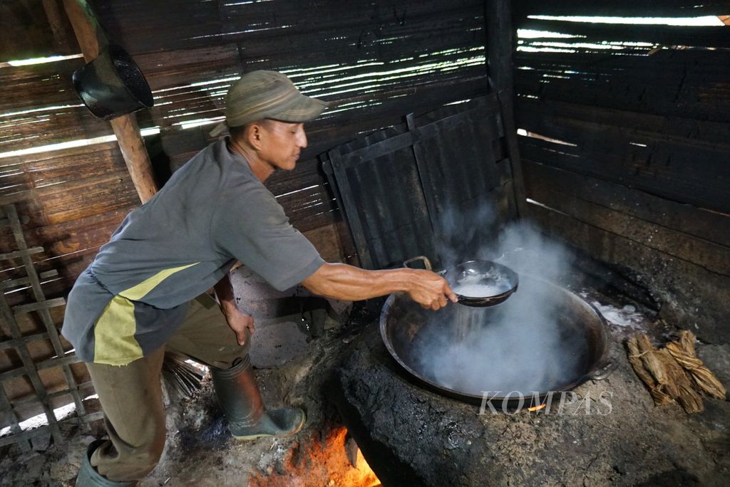 Nurdin Maletang, seorang petani gula aren, menyaring air nira yang sedang direbus dalam proses pembuatan gula aren, Selasa (19/7/2022), di perkebunan rakyat Desa Tapa Aog, Lolayan, Bolaang Mongondow, Sulawesi Utara.