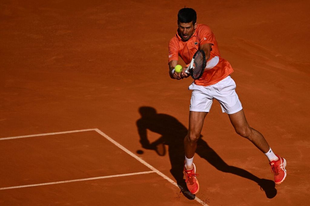 Petenis Serbia Novak Djokovic mengembalikan bola ke petenis Spanyol Carlos Alcaraz pada semifinal ATP Madrid Terbuka, di lapangan tanah liat Caja Magica, Madrid, Sabtu (7/5/2022). Pada laga itu, Alcaraz menang dengan skor 6-7 (5), 7-5, 7-6 (5). 