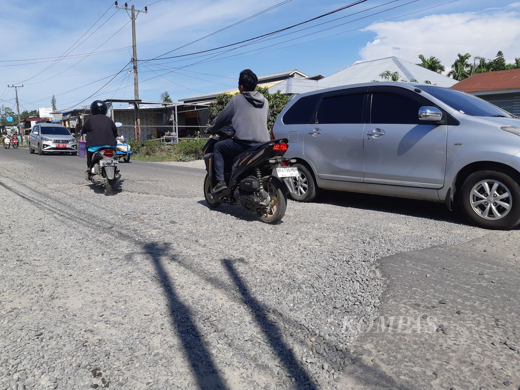Kendaraan melambat saat melintasi Jalan Medan-Percut yang rusak di Kecamatan Percut Sei Tuan, Kabupaten Deli Serdang, Sumatera Utara, Sabtu (20/5/2023). 