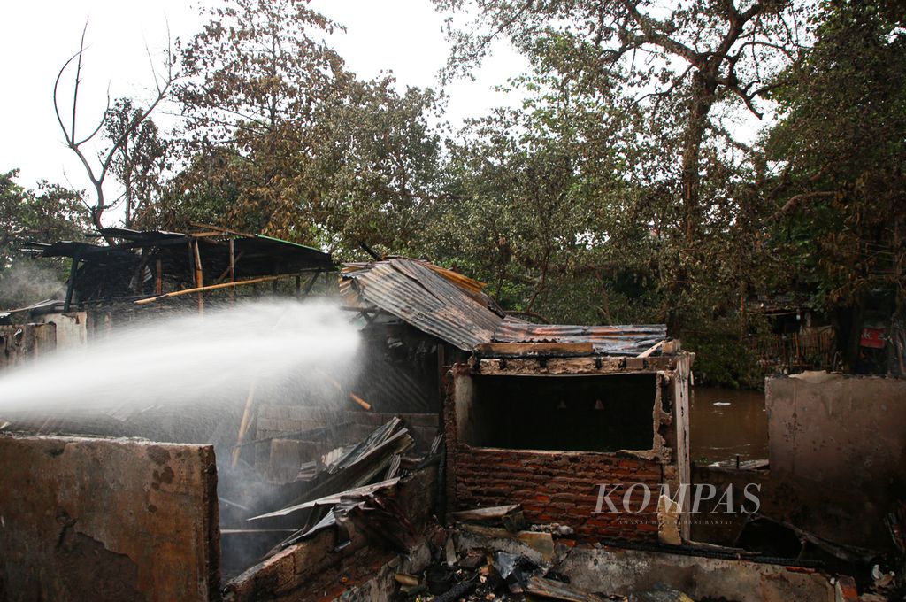 Air disemprotkan petugas pemadam kebakaran ke puing-puing rumah semipermanen yang habis terbakar di kawasan Manggarai, Tebet, Jakarta Selatan, Sabtu (17/12/2022).