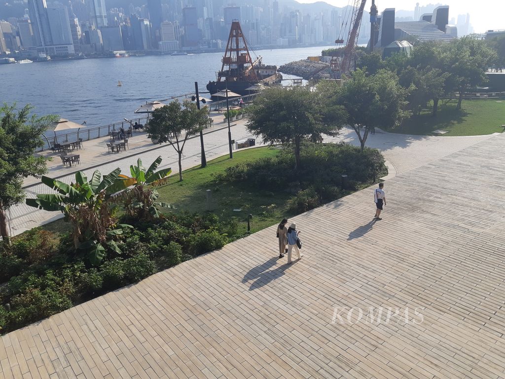 Warga berjalan santai di tepian Pelabuhan Victoria, Hong Kong, Senin (25/3/2024). 