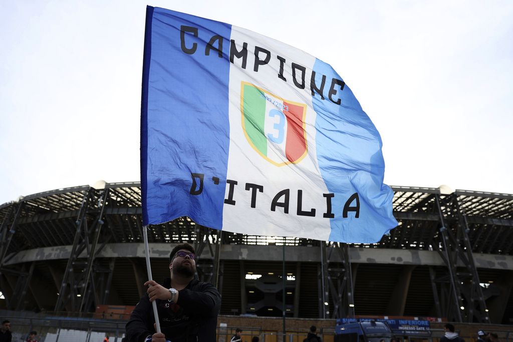 Suporter Napoli mengibarkan bendera di Stadion Diego Armando Maradona, Napoli, Minggu (2/4/2023), untuk mendukung klub kesayangannya yang sudah di ambang juara Liga Italia, 