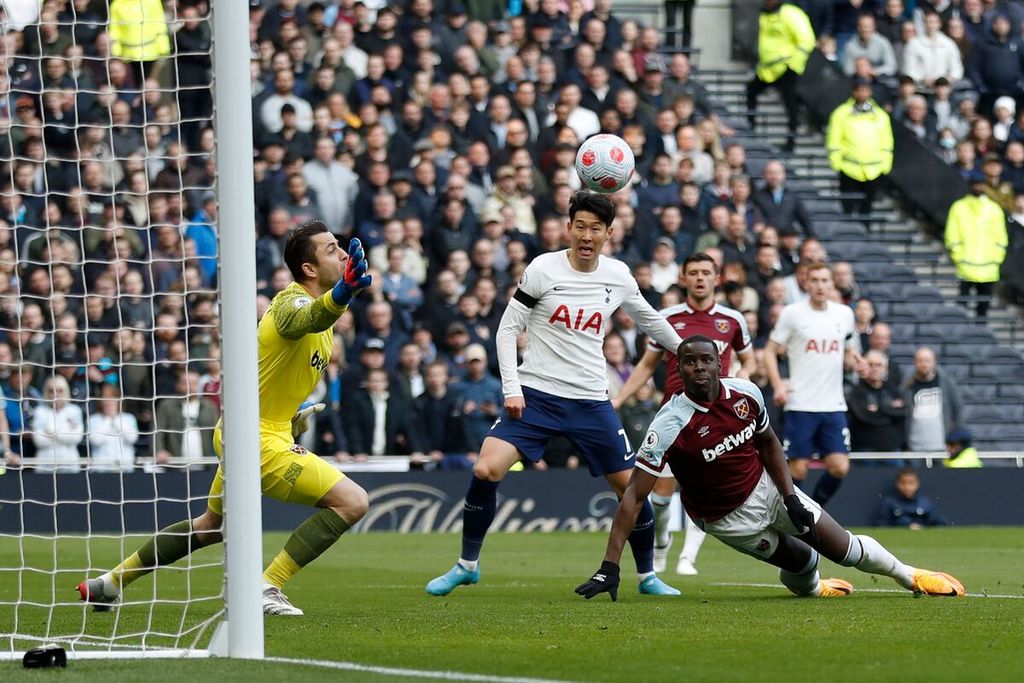Pemain West Ham United Kurt Zouma (kanan) membelokkan bola ke gawangnya sendiri saat mengadang pemain Tottenham Hotspur Son Heung-Min (tengah) pada laga Liga Inggris di Stadion Tottenham Hotspur, London, 20 Maret 2022. Spurs menang dengan skor 3-1. 