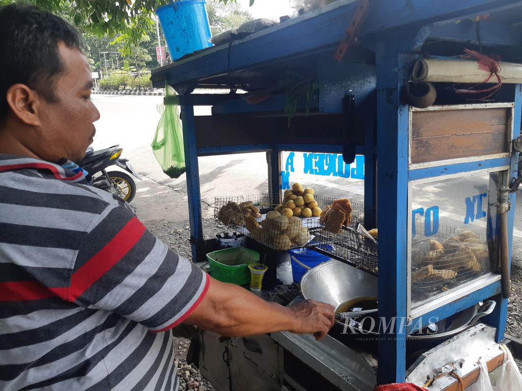Sahidin (48) menggoreng adonan tempe dan tahu di gerobaknya di Jalan Brigjen Dharsono, Kota Cirebon, Jawa Barat, Selasa (8/3/2022). Sahidin mengeluhkan harga minyak goreng curah yang mencapai Rp 18.000 per liter, naik dibandingkan biasanya, Rp 11.000 per liter.