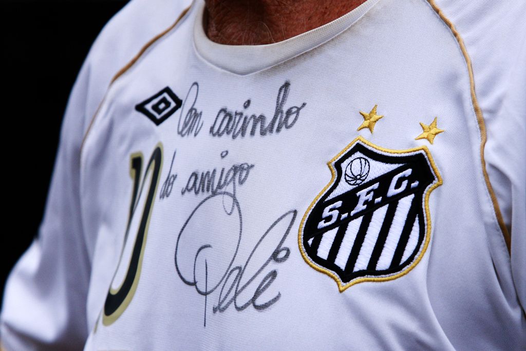 Seorang penggemar mengenakan jersei klub Santos dengan tanda tangan legenda sepak bola Brasil, Pele, di luar Stadion Vila Belmiro, Santos, Brasil, Kamis (29/12/2022). 