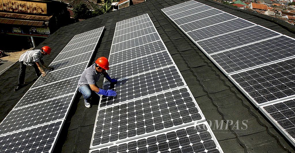 Petugas dari PLN memeriksa panel surya yang terpasang di salah satu rumah warga di Jalan Citamiang, Bandung, Jawa Barat, yang juga berfungsi sebagai PLTS Rooftop, Jumat (7/8/2015).  