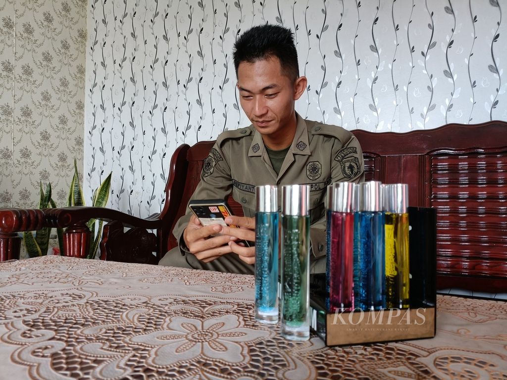 Refianto, penerima program Kartu PraKerja yang bekerja sebagai pegawai honorer di Satuan Polisi Pamong Praja Kabupaten Sintang, Kalimantan Barat, tengah melayani pembelian parfum secara daring menggunakan telepon seluler di kediamannya di Kapuas Kiri Hulu, Kecamatan Sintang, Senin (29/8/2022).