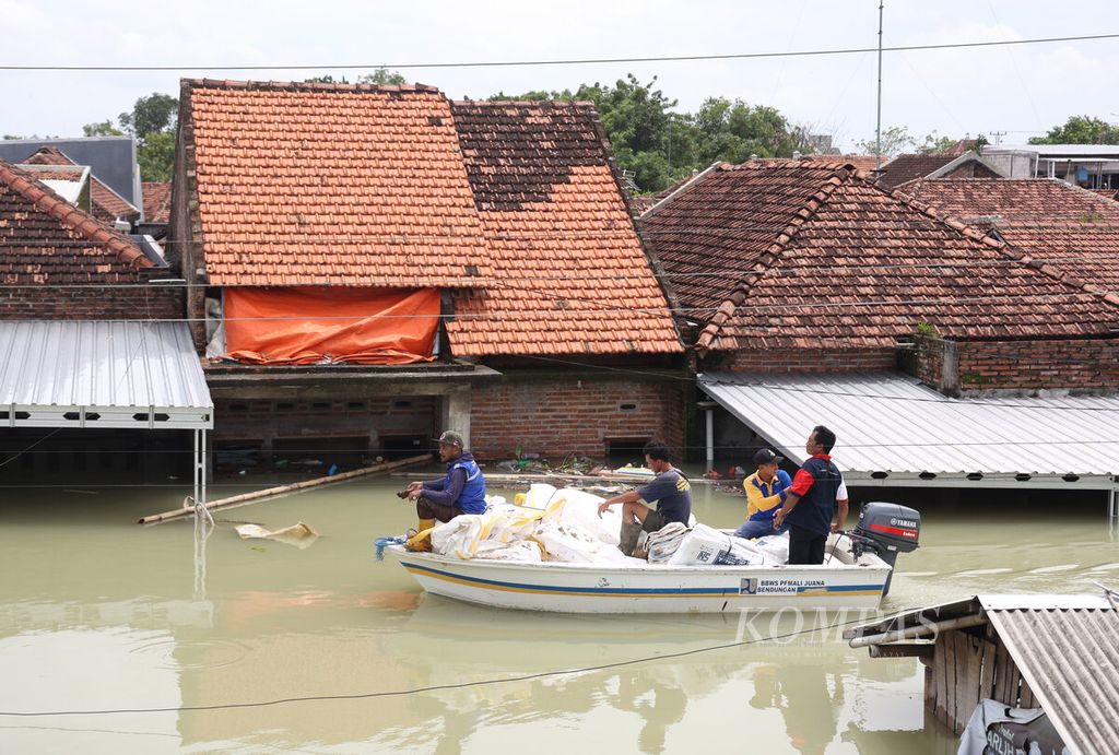 Perahu pekerja melintas di antara rumah warga yang terendam banjir saat menuju lokasi jebolnya tanggul Sungai Wulan di Desa Ketanjung, Kecamatan Karanganyar, Kabupaten Demak, Jawa Tengah, Minggu (17/3/2024). 