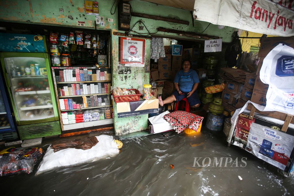 Pedagang menunggu pembeli di kiosnya yang terendam banjir di Kelurahan Kapuk, Kecamatan Cengkareng, Jakarta Barat, Jumat (22/3/2024). Banjir tersebut disebabkan curah hujan yang tinggi sejak dini hari.