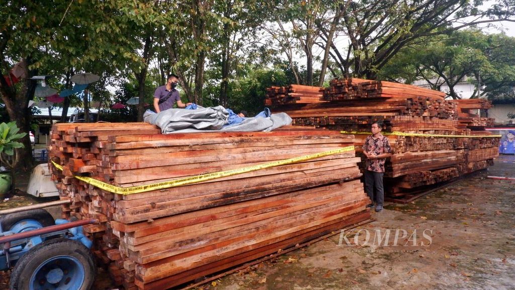 Petugas memasang garis polisi pada tumpukan kayu olahan yang disita di Banjarmasin, Kalimantan Selatan, Jumat (18/3/2022). Sebanyak 5.370 batang atau lebih kurang 76,43 meter kubik kayu olahan dari berbagai jenis kayu hutan itu ilegal karena tidak dilengkapi dokumen yang sah.