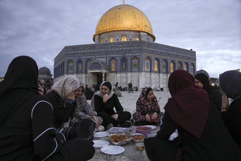 Warga Muslim Palestina berbuka puasa Ramadhan di luar bangunan Kubah Batu (Dome of Rock) di kompleks Masjid Al-Aqsa di Kota Tua Jerusalem pada 16 Maret 2024.  