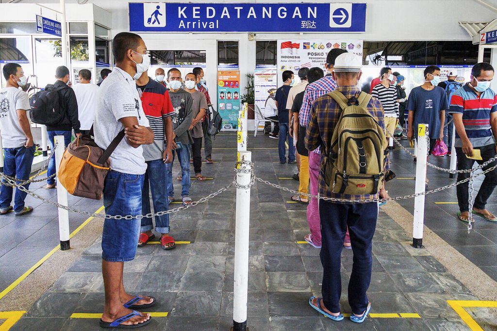 Para pekerja migran Indonesia tengah menunggu petugas mengecek kesehatan dan dokumen imigrasi mereka di pintu kedatangan Pelabuhan Internasional Batam Centre, Kota Batam, Kepulauan Riau, Kamis (21/5/2020). Selanjutnya mereka akan menjalani karantina di Rumah Susun Tanjung Uncang, Batam.