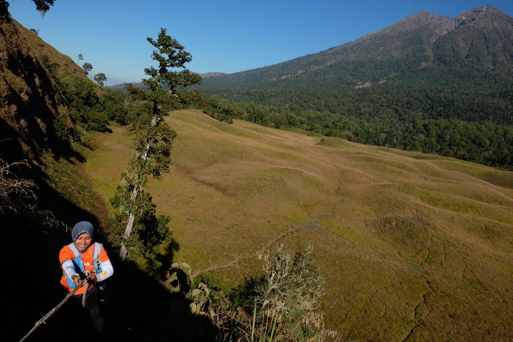 Dewi Ekawati (43), yang mengikuti Effort Challenge 2020 yang diselenggarakan Trail Running Connect, berpegangan pada tali saat menaiki bukit di kawasan Taman Nasional Gunung Rinjani, tepatnya di Savana Propok, Desa Bebidas, Kecamatan Wanasaba, Lombok Timur, Nusa Tenggara Barat, Sabtu (28/8/2020). Effort Challenge 2020 merupakan lomba lari <i>trail </i>yang berlangsung selama 28 hari dan diikuti hampir 200 pelari dari seluruh wilayah Indonesia.