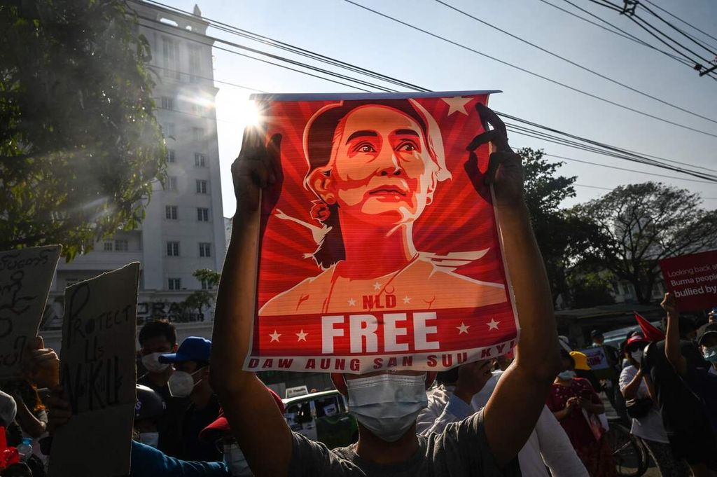 Foto yang diambil pada 15 Februari 2021 ini memperlihatkan seorang pengunjuk rasa mengangkat poster bergambar Aung San Suu Kyi dalam unjuk rasa menentang kudeta militer di gedung Bank Sentral Myanmar di Yangon, Myanmar. 