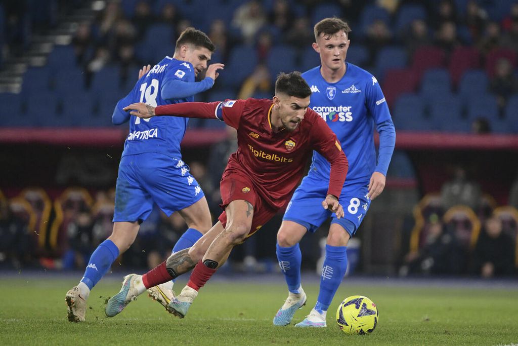 Pemain AS Roma Lorenzo Pellegrini meliuk-liuk melewati dua pemai Empoli, Razvan Marin (kiri) dan Liam Henderson dalam pertandingan Liga Italia antara AS Roma dan Empoli di Stadion Olimpico, Roma, Minggu (5/2/2023). AS Roma mengalahkan Empoli, 2-0. 