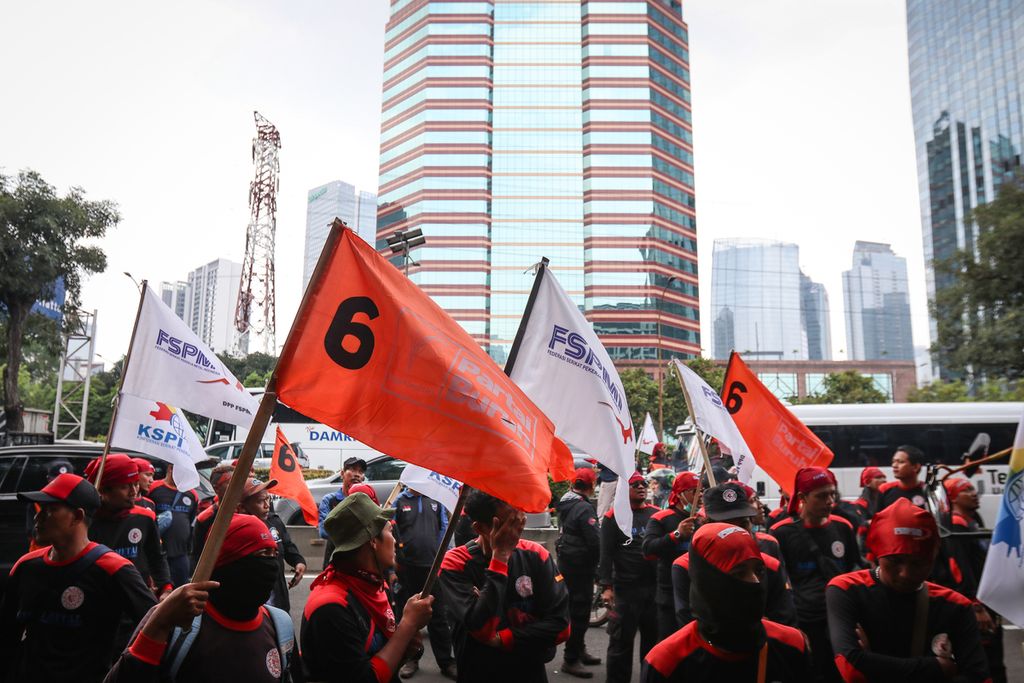 Para buruh membawa bendera Partai Buruh dan bendera sejumlah serikat buruh saat aksi di depan Kantor Direktorat Jenderal Pajak Kementerian Keuangan, Jakarta, Jumat (10/3/2023). 