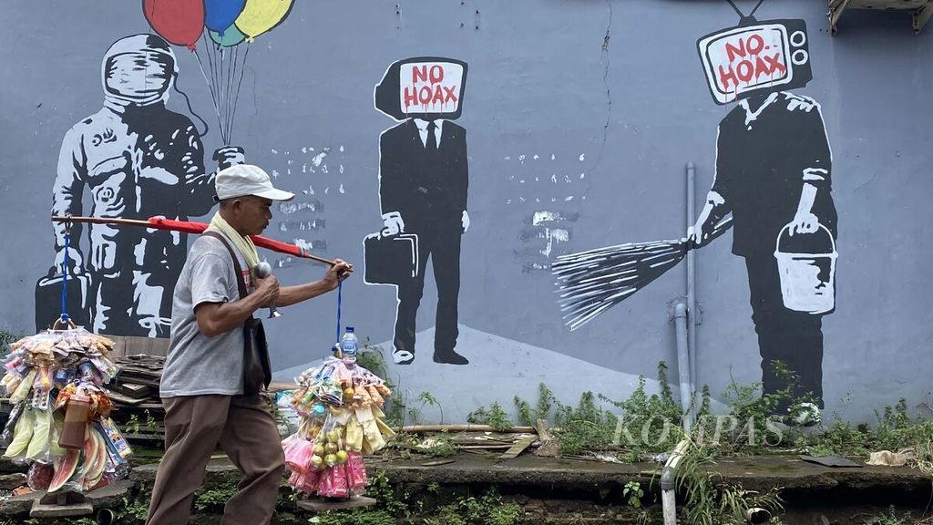 Warga melintasi mural yang dibuat untuk melawan penyebaran informasi palsu di masyarakat atau hoaks di Jalan KH Hasyim Ashari, Tangerang, Banten, Senin (22/2/2021). 