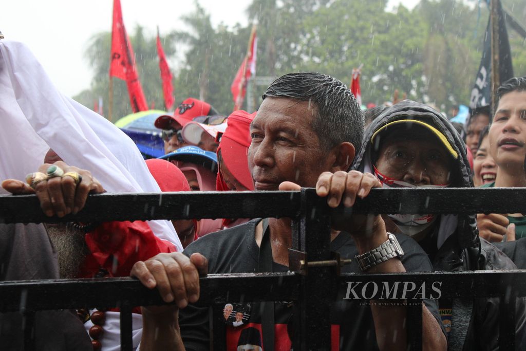 Para pendukung Ganjar Pranowo-Mahfud MD menunggu kedatangan Ganjar di tengah hujan saat kampanye akbar bertajuk "Hajatan Rakyat" di Lapangan Tegalega, Kota Bandung, Jawa Barat, Minggu (21/1/2024).