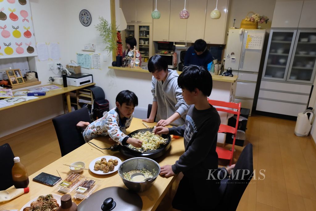Ketiga anak keluarga Higashiuchi memasak takoyaki di kediamannya di kota Isahaya, Prefektur Nagasaki, Jepang, Sabtu (27/1/2024). Menurut mereka, membuat takoyaki adalah kegiatan keluarga yang biasanya mereka lakukan sekitar sebulan sekali. Selain takoyaki, ayah dan ibunya juga menyiapkan menu lain di meja makan, seperti daging tumis, sayur, dan buah.