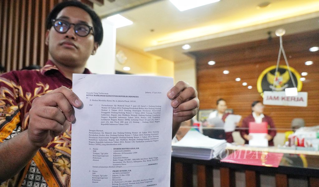 Seorang anggota Aliansi Gerakan Peduli Hukum menunjukkan surat permohonan judicial review yang ditujukan kepada Mahkamah Konstitusi, Jakarta, terkait batas usia calon peserta Pilkada 2024, Kamis (18/7/2024). KOMPAS/RONY ARIYANTO NUGROHO 18-7-2024