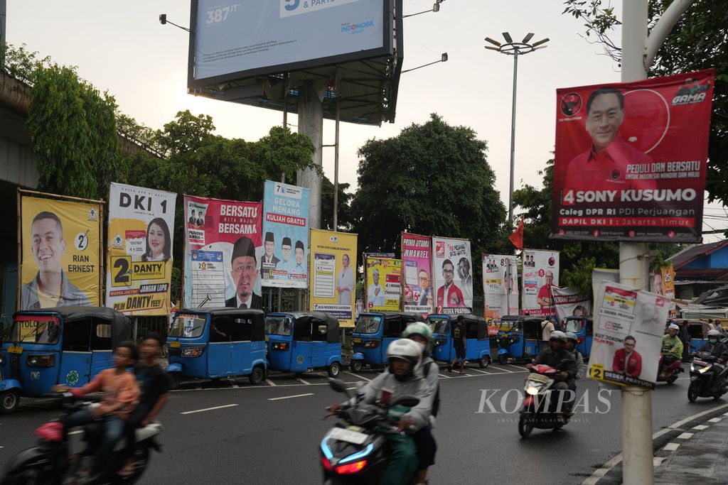 Residents pass by billboards for legislative candidates in Kampung Melayu, East Jakarta, Monday (5/2/2024).