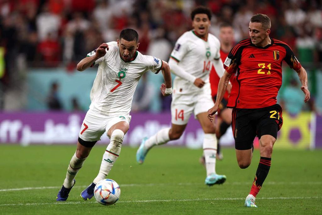 Pemain timnas Maroko Hakim Ziyech (kiri) menggiring bola dengan dibayangi oleh pemain timnas Belgia Timothy Castagne pada pengisihan Grup F Piala DUnia Qatar 2022 di Stadion Al-Thumama, Doha, Qatar, Minggu (27/11/ 2022). Maroko menang 2-0 pada laga itu 