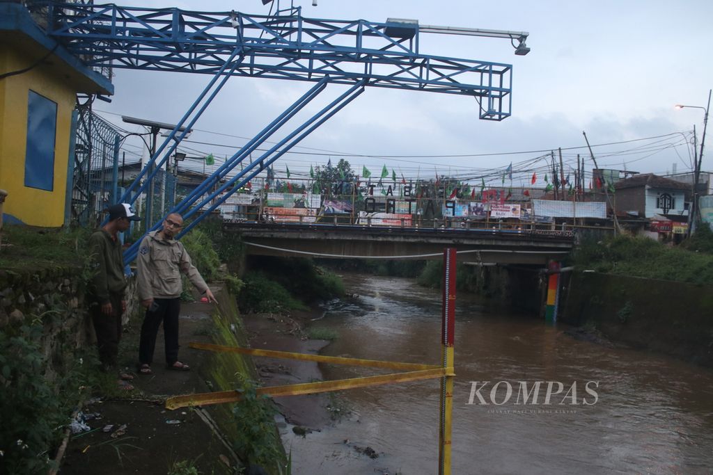 Riki Waskito (45) dan rekannya berdiskusi sambil mengamati parameter ketinggian air di badan Sungai Citarum yang melintasi Kecamatan Majalaya, Kabupaten Bandung, Jawa Barat, Kamis (2/3/2023). 