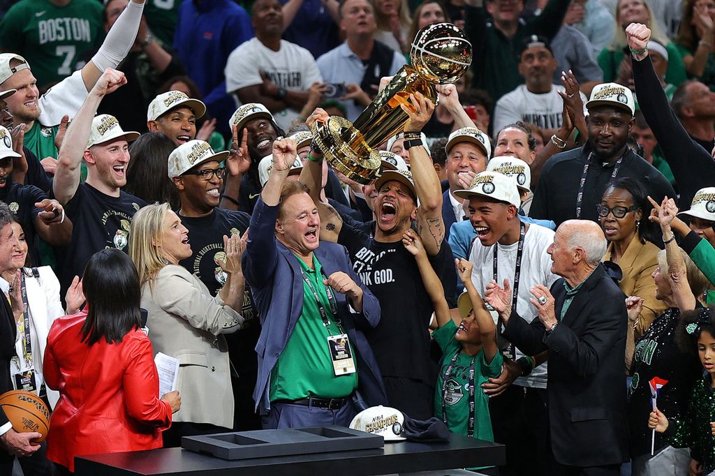 Pelatih Boston Celtics, Joe Mazzulla, mengangkat trofi Larry OBrien setelah timnya menjadi juara NBA. Celtics mengalahkan Dallas Mavericks dengan skor 106-88 pada gim 5 Final NBA di Stadion TD Garden, Boston, Senin (17/6/2024) atau Selasa (18/6/2024) WIB.