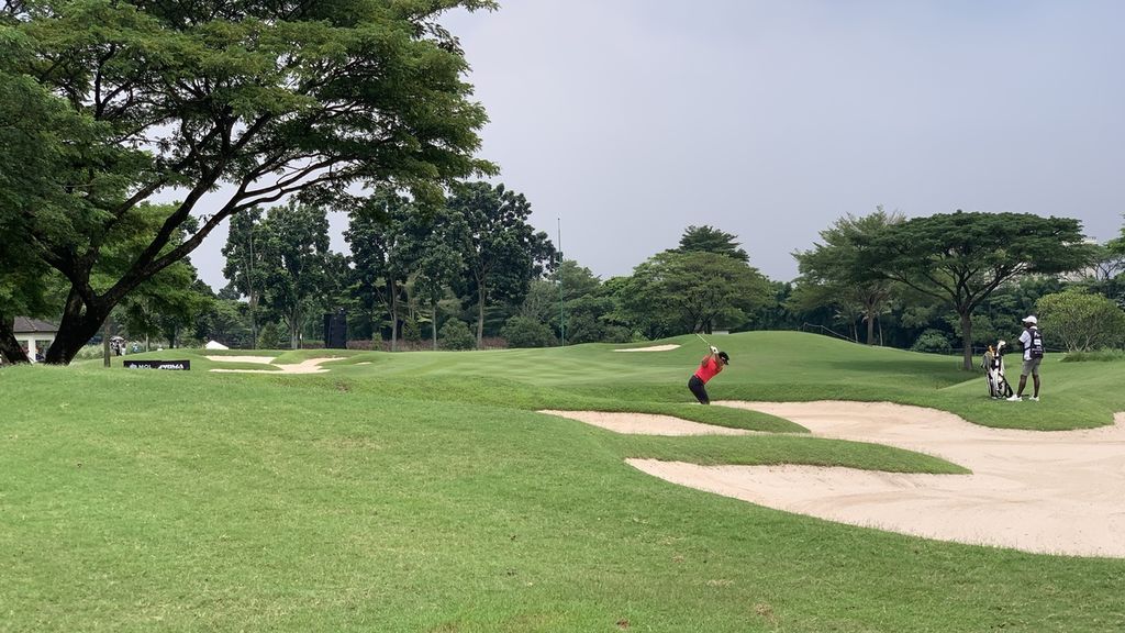 Pegolf Thailand, Sarit Suwannarut (merah), memukul bola keluar <i>bunker </i>pasir pada turnamen golf Indonesian Master 2022 di Royale Jakarta Golf Club, Jakarta, Minggu (4/12/2022). 