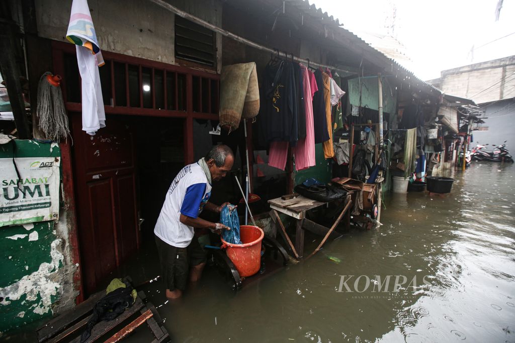 Warga mencuci pakaian di tengah banjir yang merendam huniannya di kawasan padat di Kelurahan Kapuk, Kecamatan Cengkareng, Jakarta Barat, Jumat (22/3/2024).