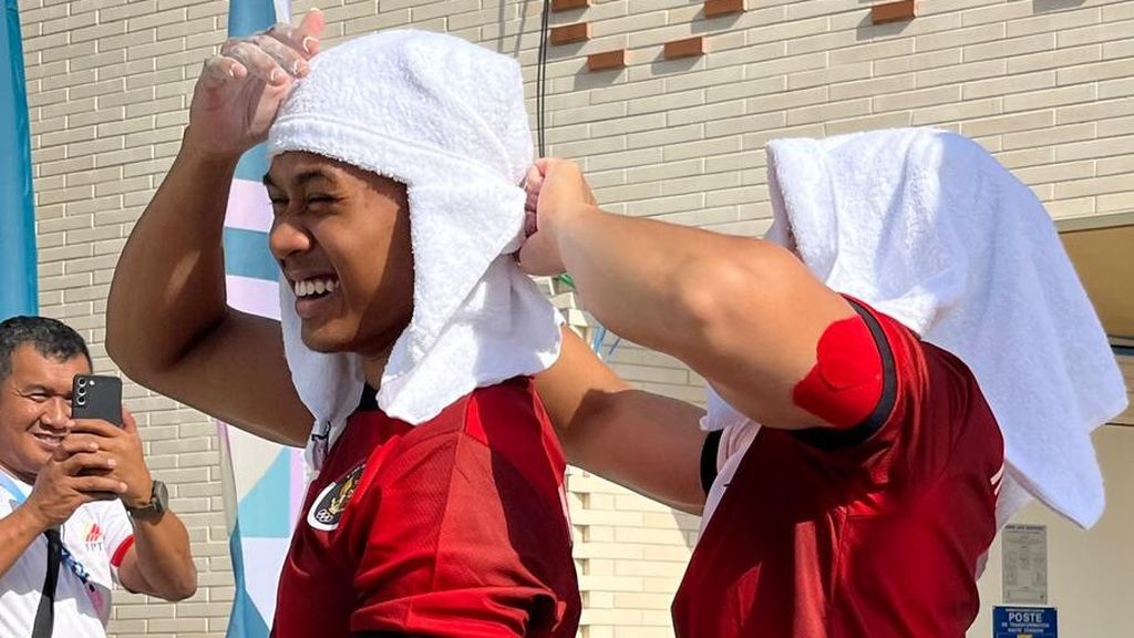 Atlet panjang tebing Indonesia nomor <i>speed </i>putri, Desak Made Rita Kusuma Dewi, mengikat handuk pendingin yang dikenakan atlet panjat nomor <i>speed </i>putra Rahmad Adi Mulyono menjelang latihan di Le Bourget Climbing Arena, Saint-Dennis, Paris, Perancis, Rabu (31/7/2024). 