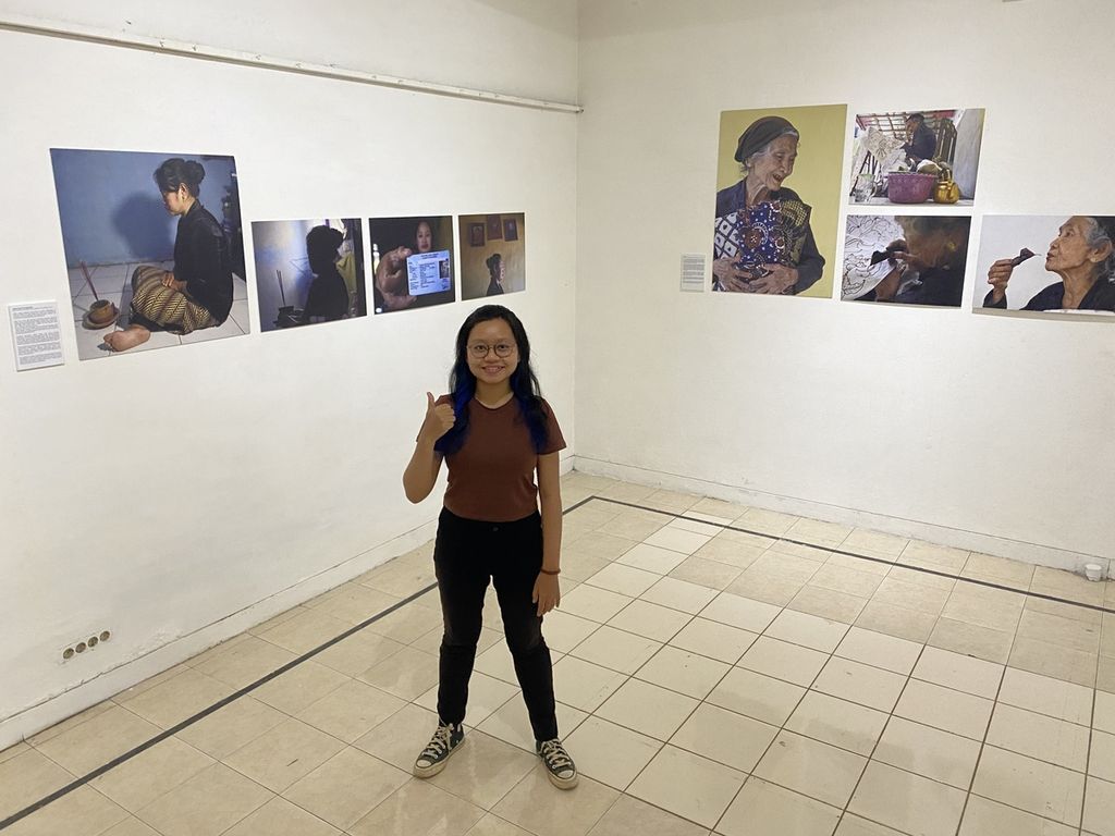 Wartawan harian <i>Kompas,</i> Kristi Dwi Utami, berfoto di galeri dengan latar belakang foto-foto karyanya di pameran Kisah Perempuan Pesisir.