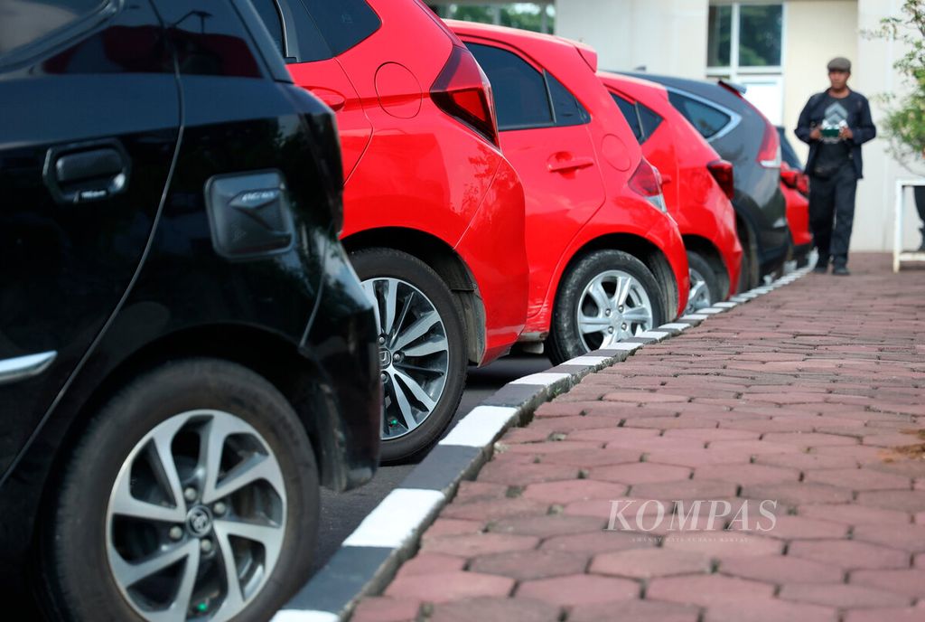 Salah satu anggota polisi melintasi deretan mobil yang menjadi barang bukti dari aksi komunitas <i>lengek squad</i> melakukan kejahatannya di kantor Polda Jawa Tengah, Kota Semarang, Selasa (9/1/2023). Para pelaku melancarkan aksi dengan menjual mobil berbagai merek itu tanpa kelengkapan surat resmi. Aksi komplotan ini menyasar sejumlah wilayah, antara lain Jawa Barat dan Jawa Timur, lalu dibawa ke Kabupaten Pati. 