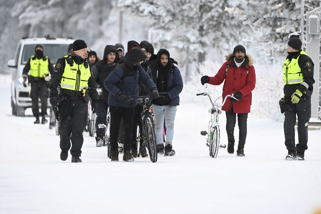 Beberapa petugas otoritas perbatasan Finlandia mengawal sejumlah migran yang tengah mencoba masuk ke negara tersebut di titik penyeberangan Salla, Finlandia, Kamis (23/11/2023). 
