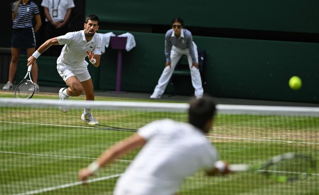 Petenis Serbia, Novak Djokovic (kiri), berlari untuk menjangkau bola pukulan lawannya, Carlos Alcaraz (Spanyol), pada final tunggal putra Grand Slam Wimbledon 2023 di The All England Tennis Club, Wimbledon, Inggris, Minggu (16/7/2023) malam.