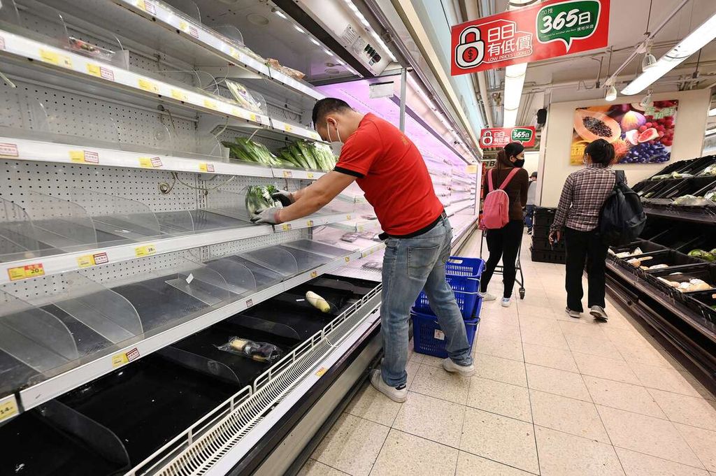 Pegawai supermarket (kiri) mengisi ulang rak-rak yang kosong setelah warga Hong Kong memborong bahan makanan menjelang rencana karantina wilayah total, 1 Maret 2022. 