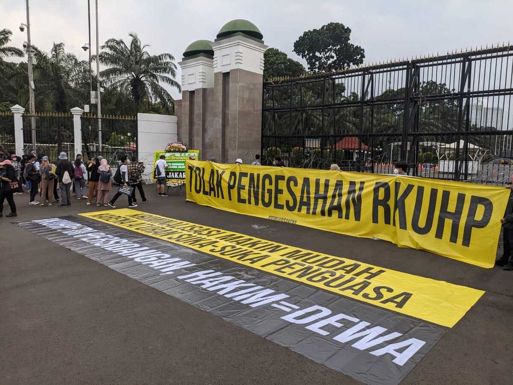 Peserta aksi membentangkan spanduk penolakan pengesahan RKUHP di gerbang utama Kompleks DPR, Senayan, Jakarta Pusat, Senin (5/12/2022). 